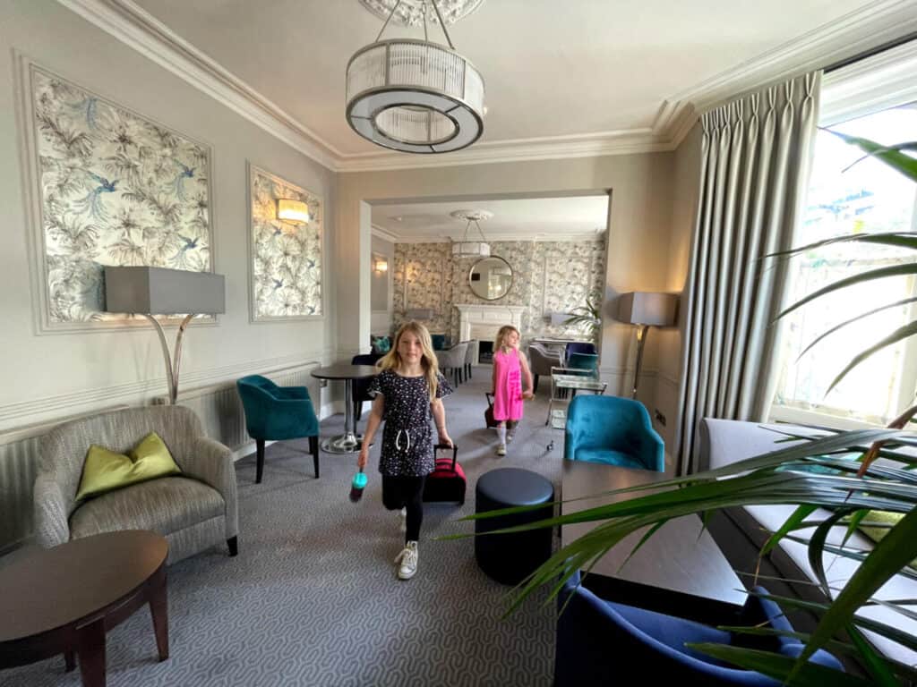 Children wheeling suitcases through a hotel lounge