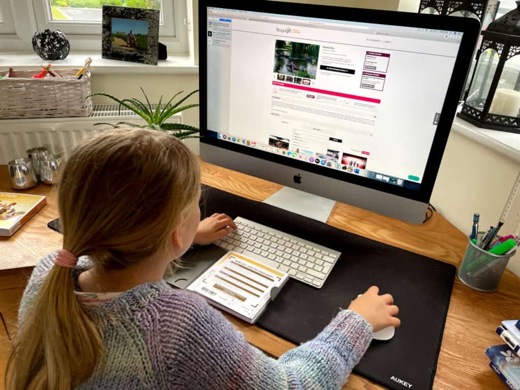Child looking at Buyagift website at desk on Mac computer