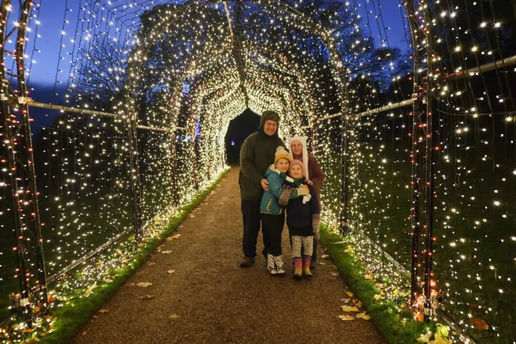 Family in the tunnel of light made iup of strings of fair lights at Killerton in Devon