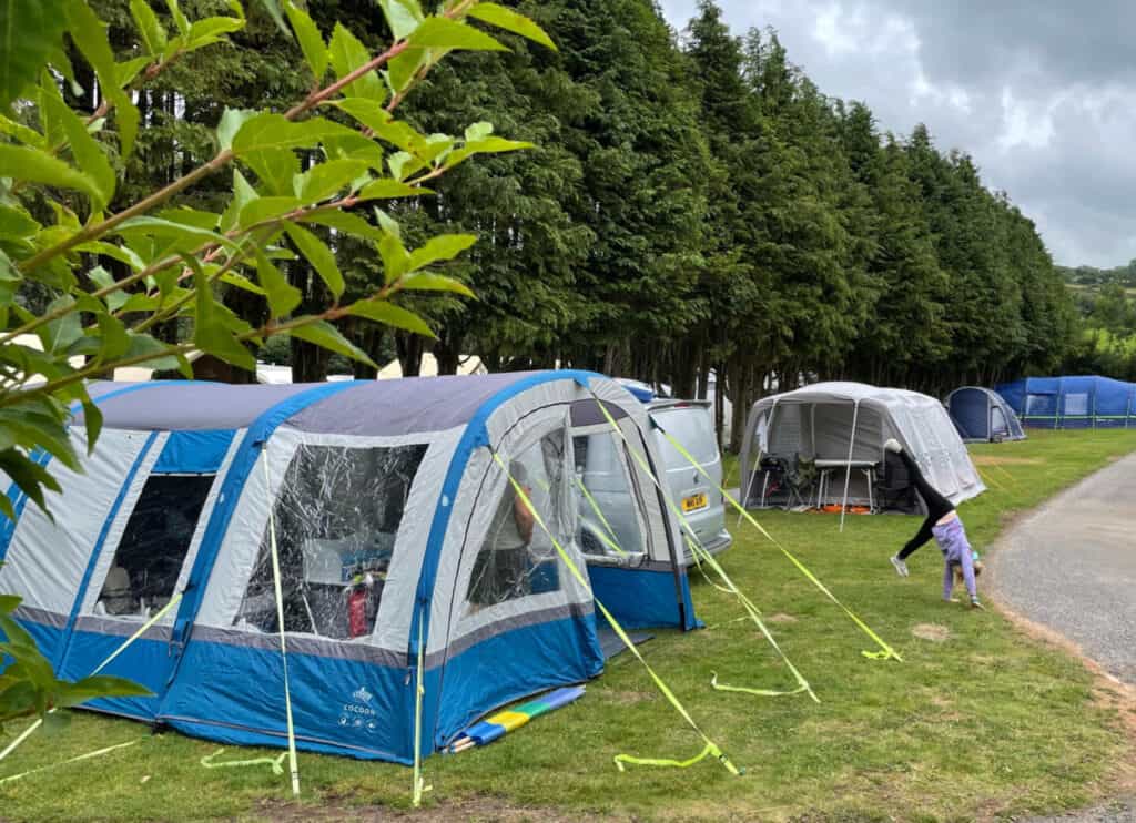 Camper van awning on pitch at California Cross campsite with Tot cartwheeling in front of it
