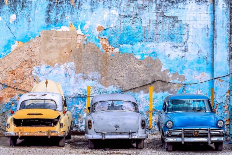 Three colourful Cuban cards agains a peeling blue painted wall