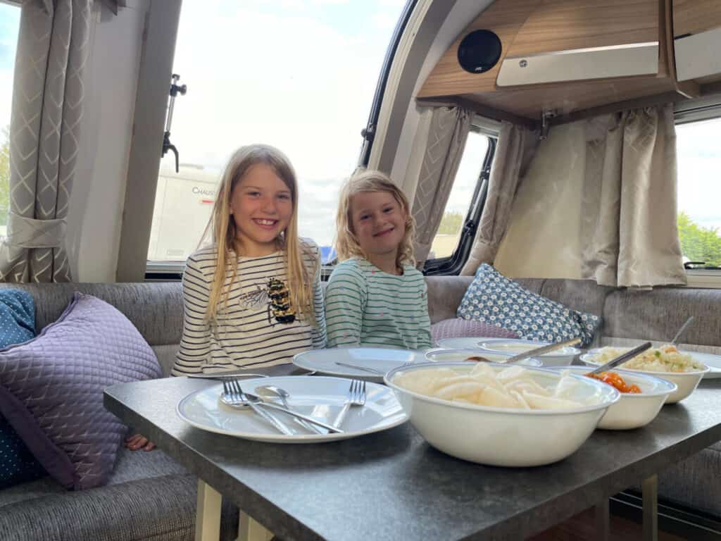 Children sat at table in caravan with food in front of them