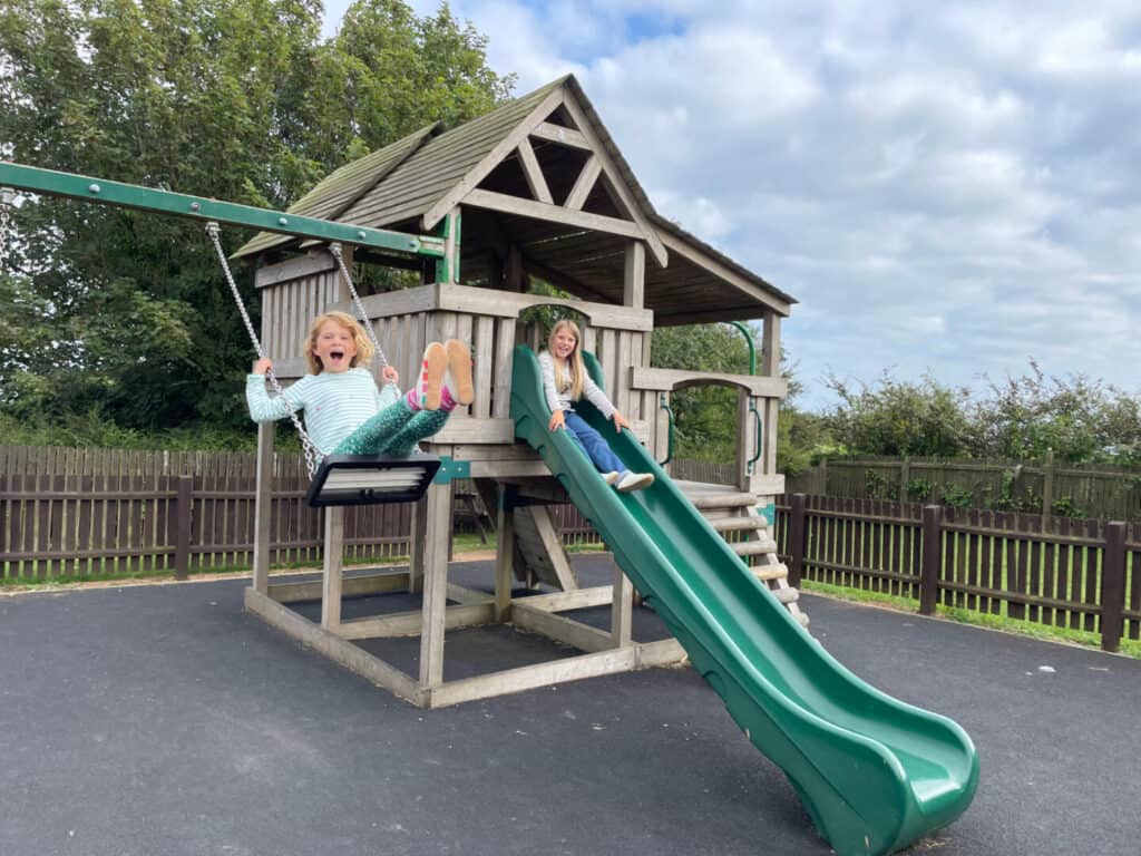 Children playing on swing and slide in playground