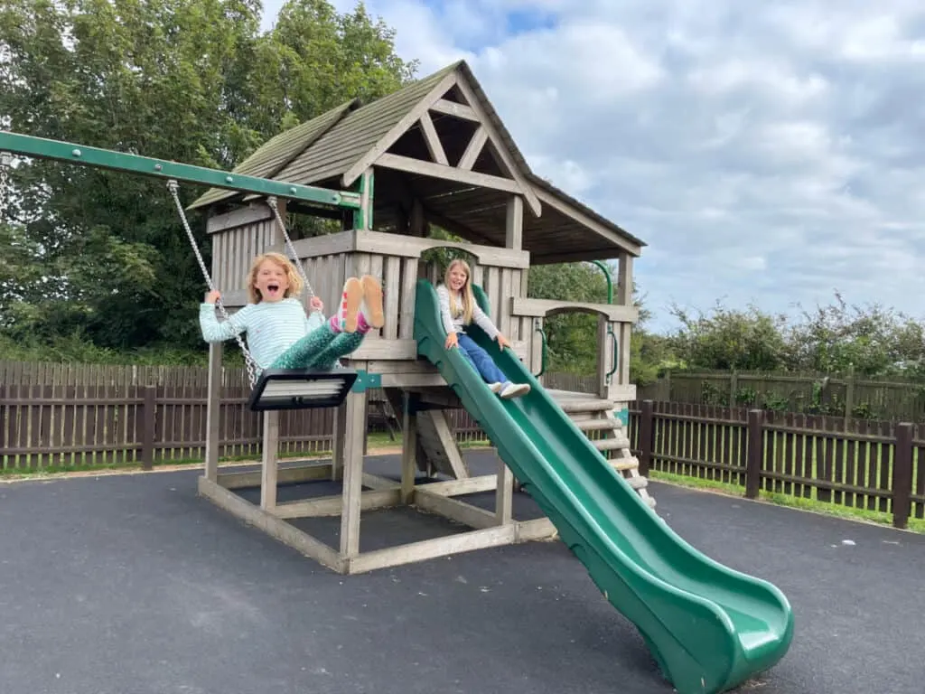 Children playing on swing and slide in playground
