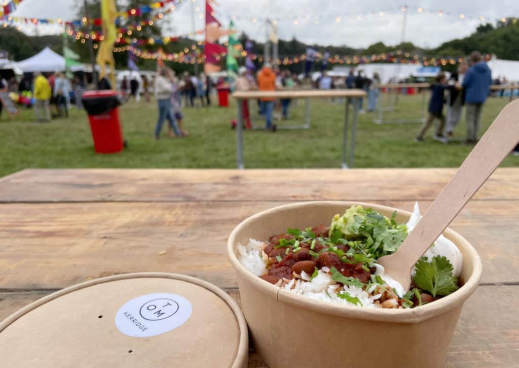 Close up of Tom Kerridge's vegan chilli with festival in background