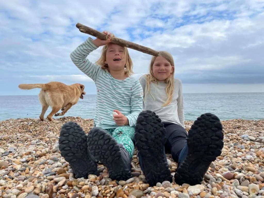 Girls sat on beach with dog running in background