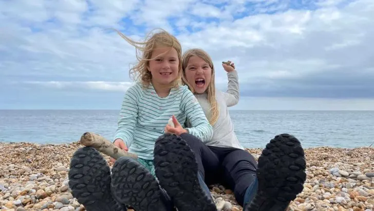 Girls sat on beach throwing stones
