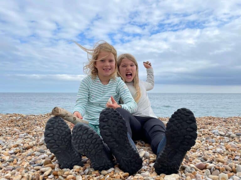 Girls sat on beach throwing stones