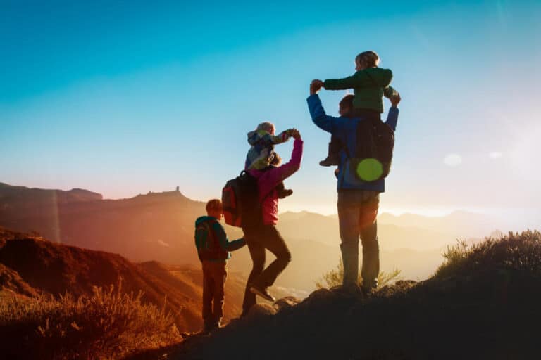 Family stood on top of hill facing the sun