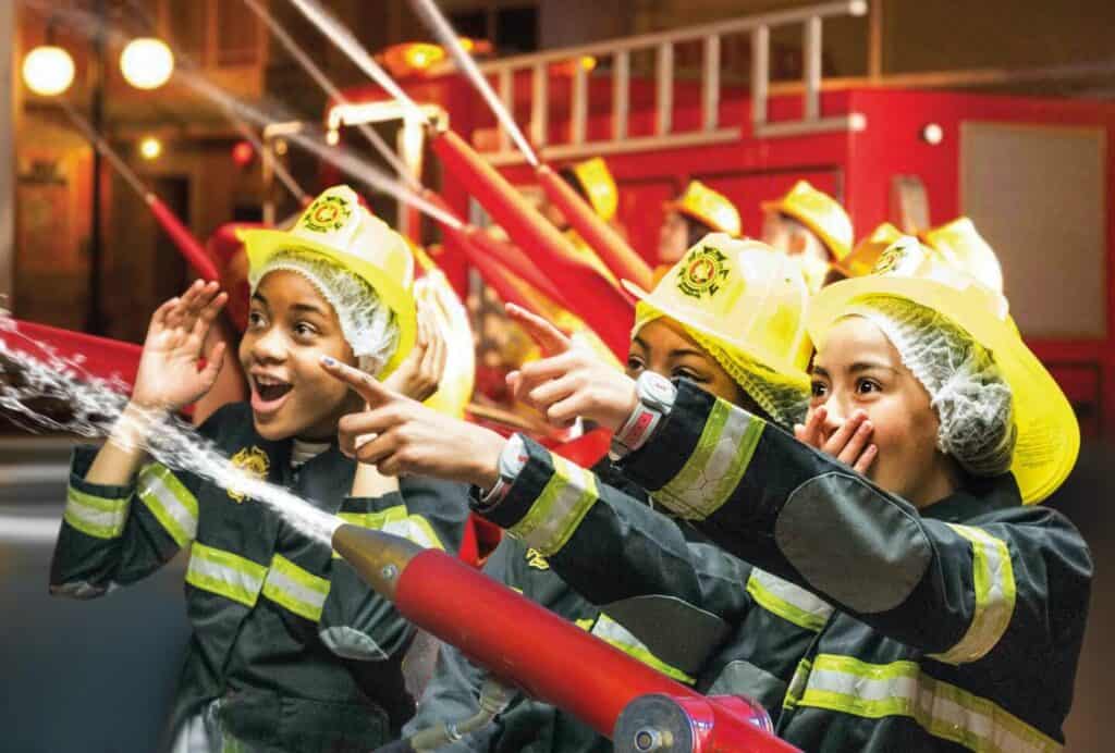 Kids dressed as fire fighters with hoses