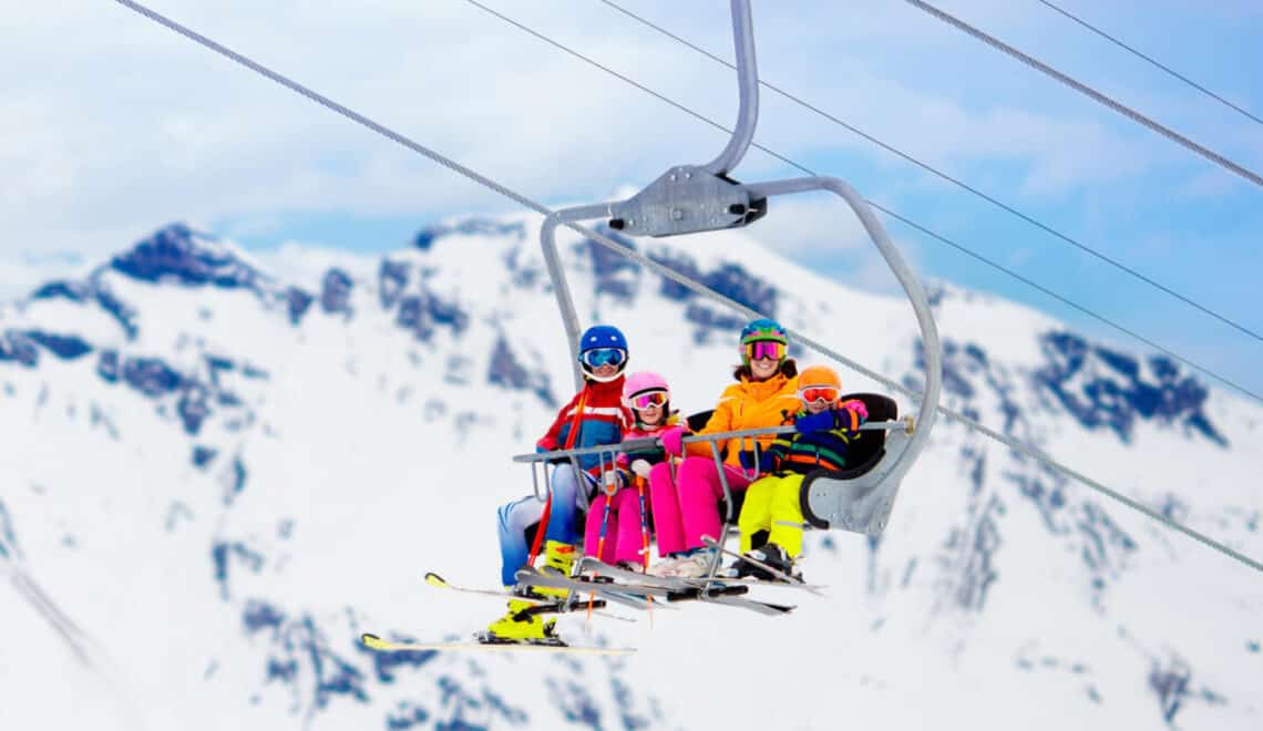 Family in ski lift in Swiss Alps mountains. Skiing with young kids. Father, mother and children sitting in ski lift during vacation. Winter outdoor sports for active family.