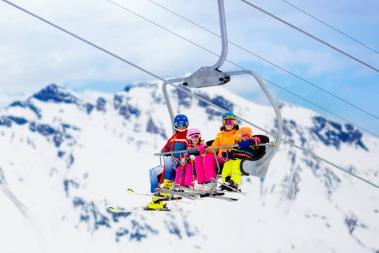 Family in ski lift in Swiss Alps mountains. Skiing with young kids. Father, mother and children sitting in ski lift during vacation. Winter outdoor sports for active family.