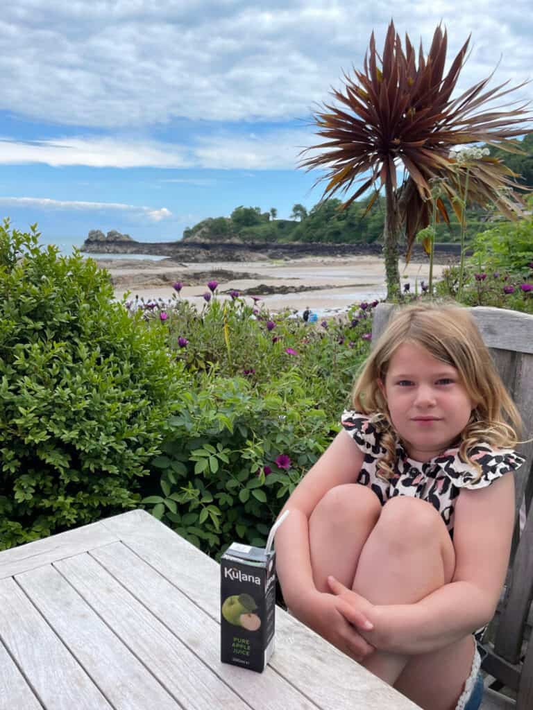 Child sat with juice box at Driftwood Cafe at Archirondel Beach