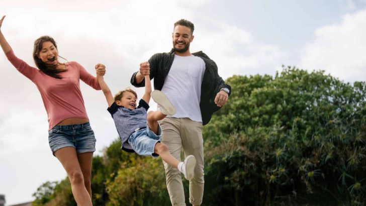 Happy couple in playful mood outdoors enjoying with their child. Cheerful family on vacation enjoying outdoors.