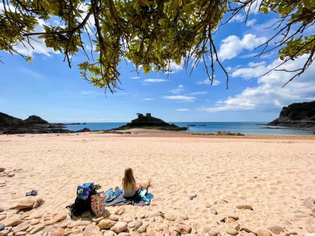 Girl sat on sand at Portlet Beach