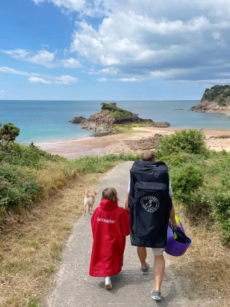 Family and dog walking down path to Portlet Beach