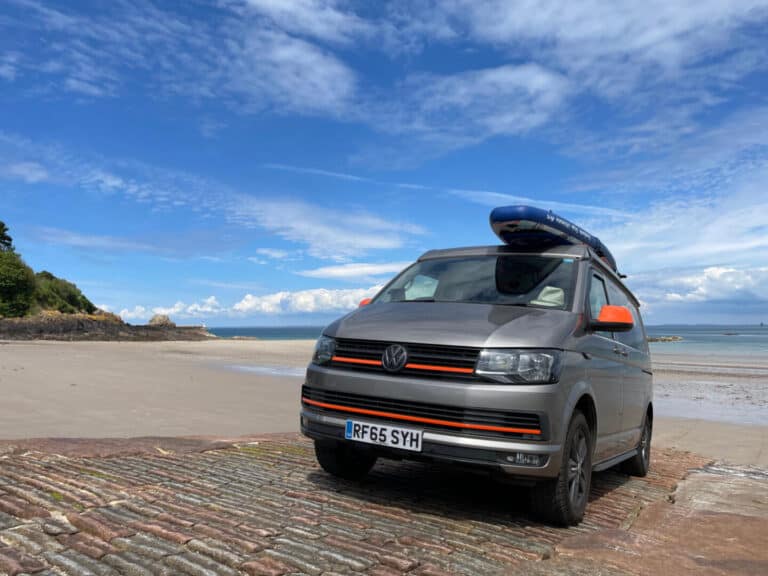 Camper van parked on slipway in front of Anne Port beach in Jersey