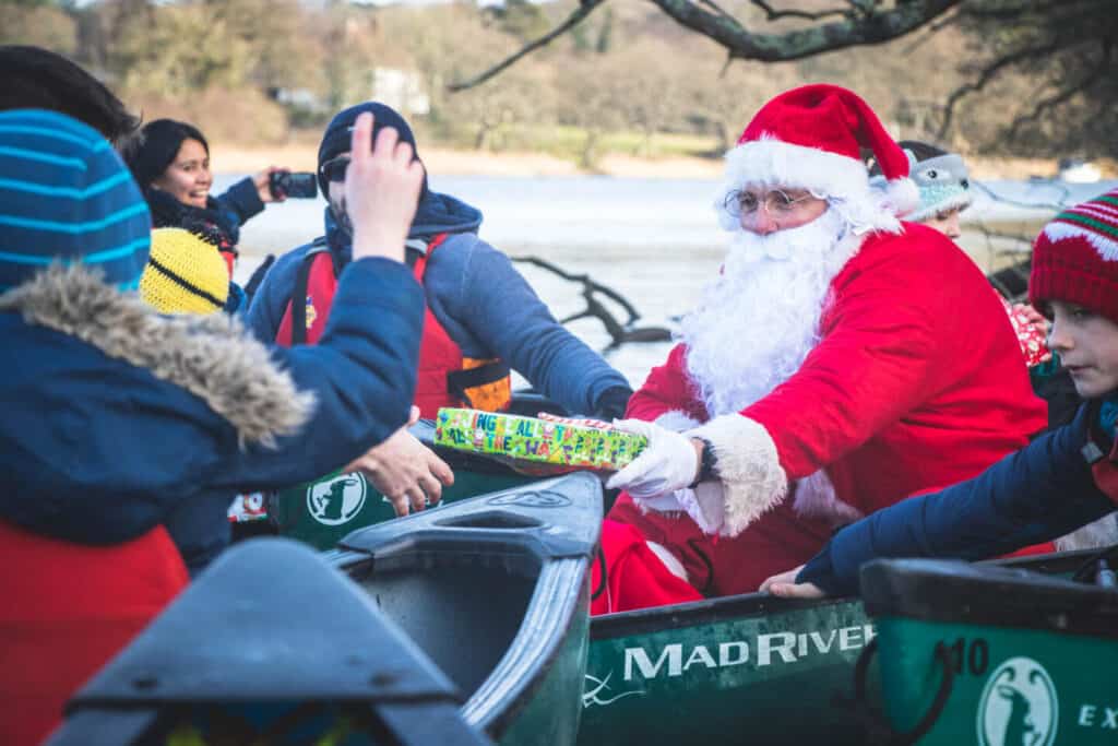 Santa handing out gifts to families on canoes