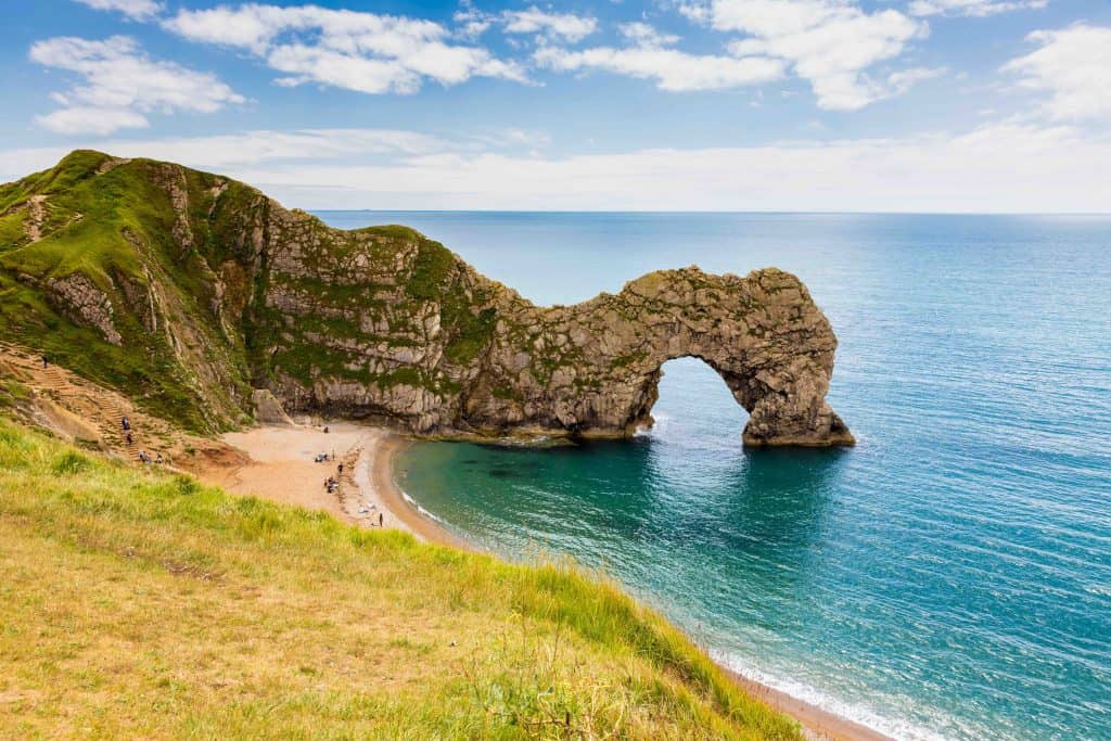 Durdle Door, travel attraction on South England, Dorset in sunny summer day with calm azure sea and blue sky. View from top of cliffs.