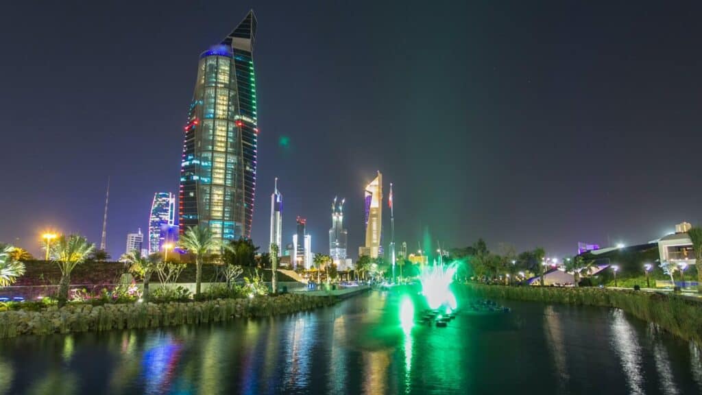 Music fountains in park with Kuwait City cityscape night timelapse hyperlapse. Modern towers reflected in the water.