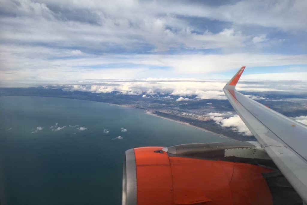 View out of an Easyjet plane window looking towards the wing. The UK coastline is below