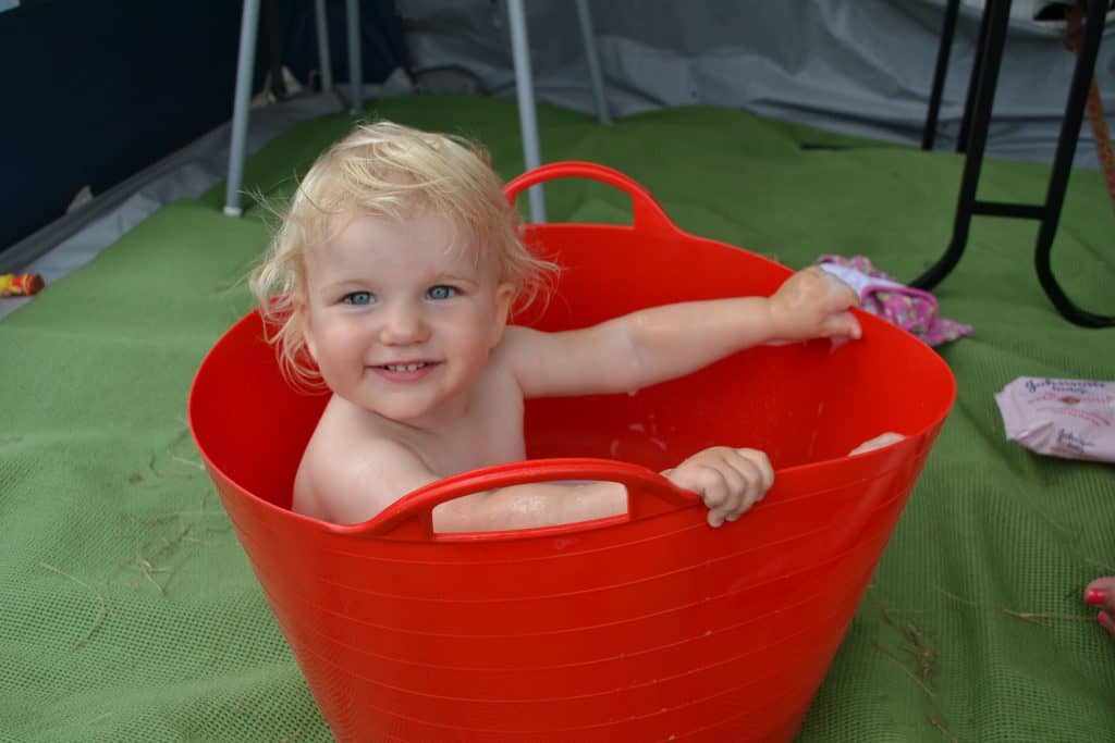 Happy toddler sat in red Flexi bucket in caravan awning