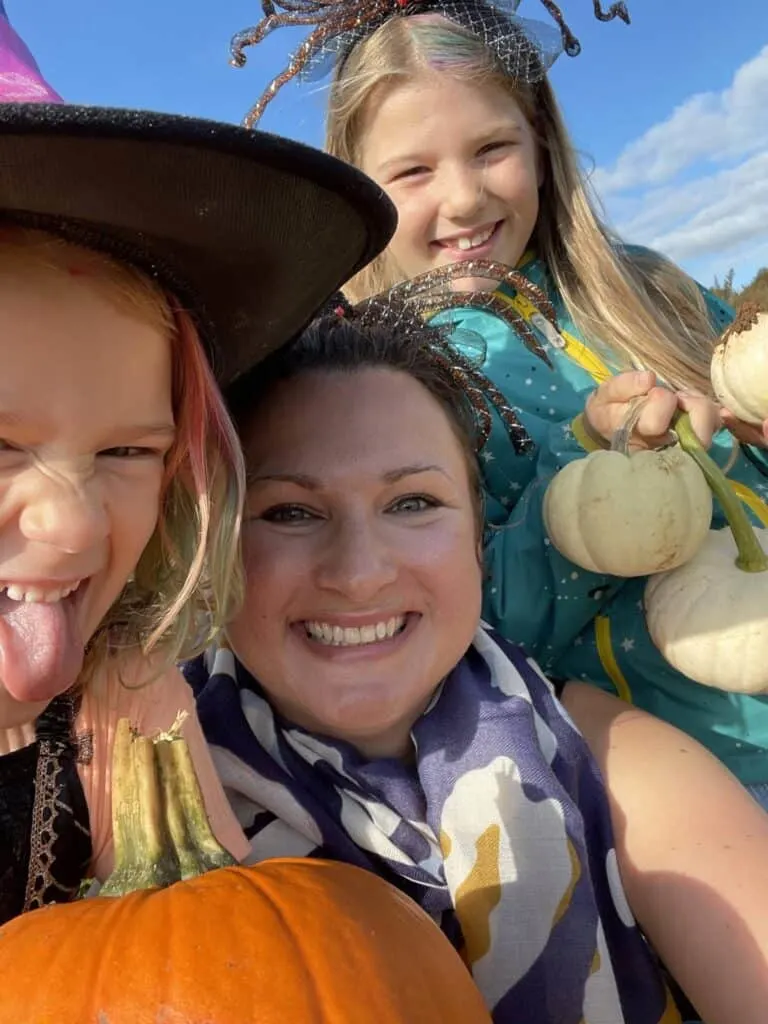 Tin Box Family selfie at pumpkin patch. Everyone is wearing Halloween costumes 