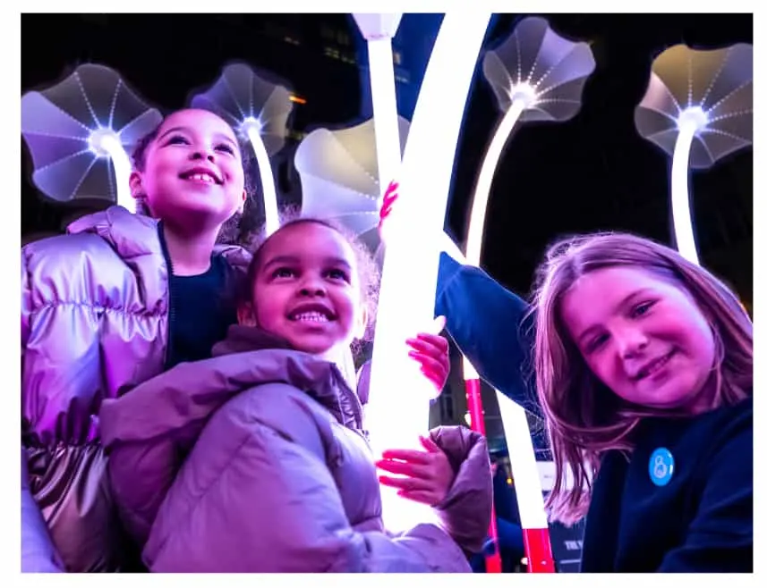 Children with illuminated art installation at night
