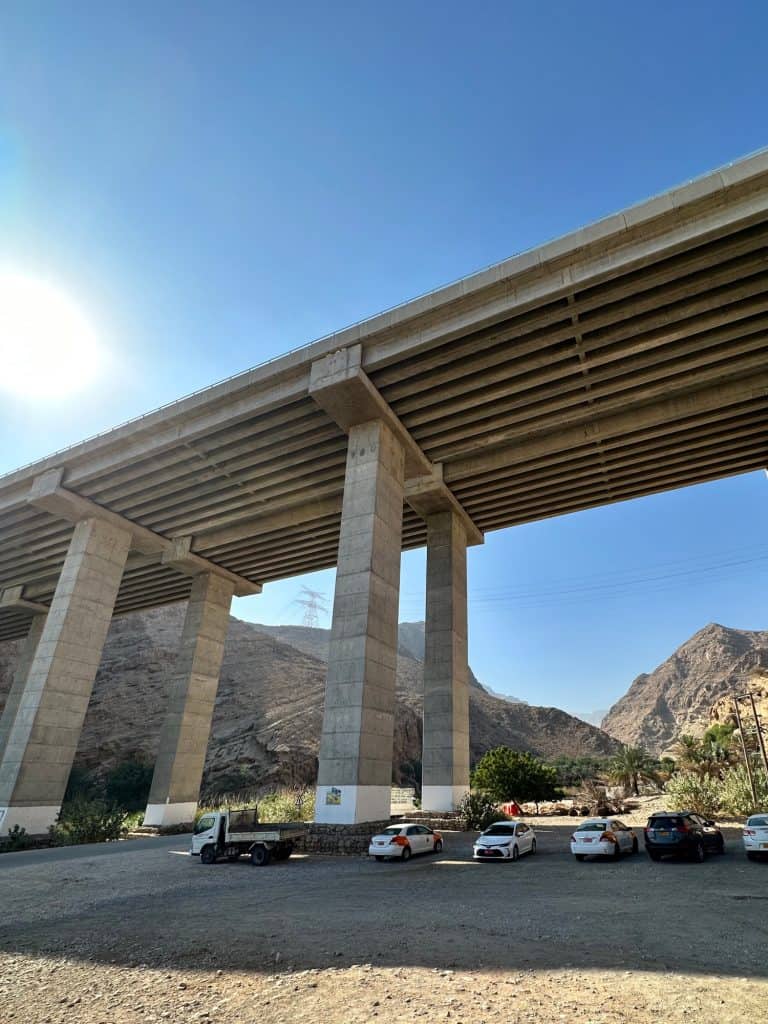 Cars parked under the wadi Tiwi viaduct which towers above them