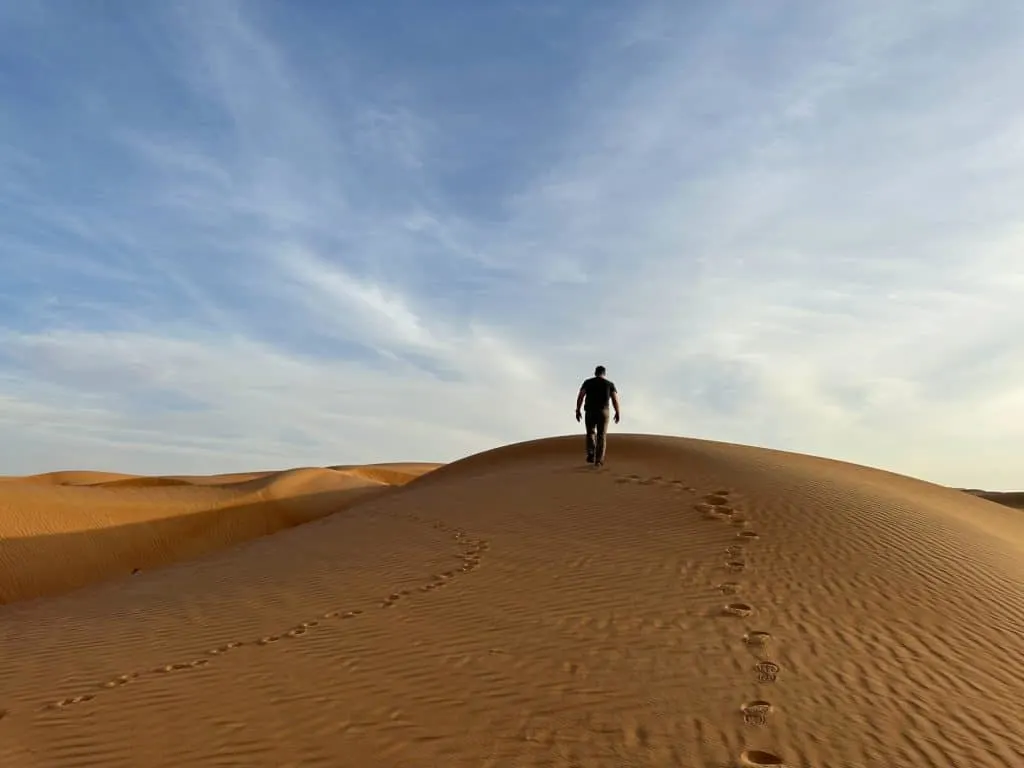 Allan climbs orange dune during sunset at Wahiba Sands in Oman