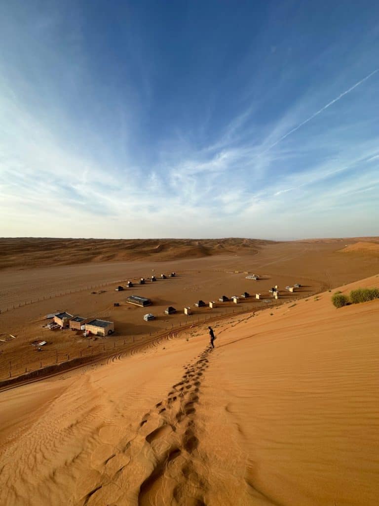 Oval of traditional bedouin black and white striped tents in the Wahiba Sands desert, Oman. Picture is taken from above on a dune at sunset