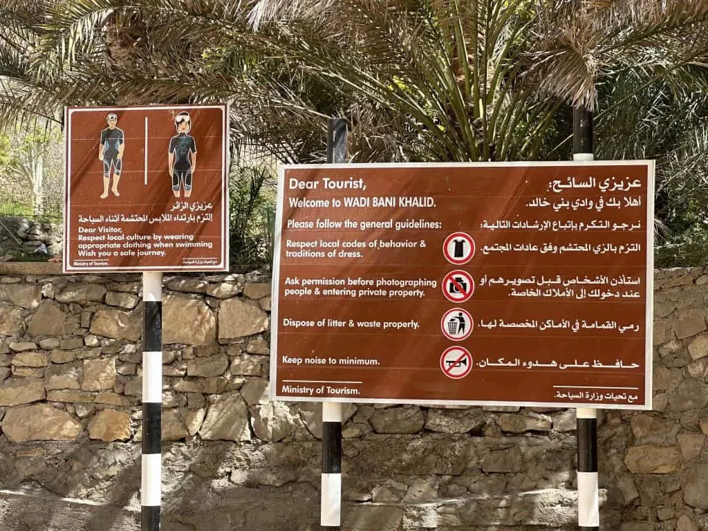 Two brown signs with guidance about what men and women should wear to visit and swim in Wadi Bani Khalid