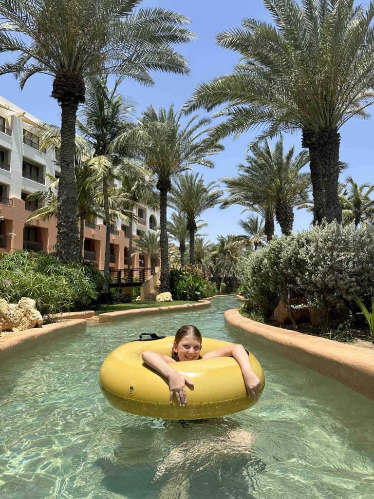 Our daughter in a yellow rubber ring floating down the lazy river at Shangri-La with the hotel in the background