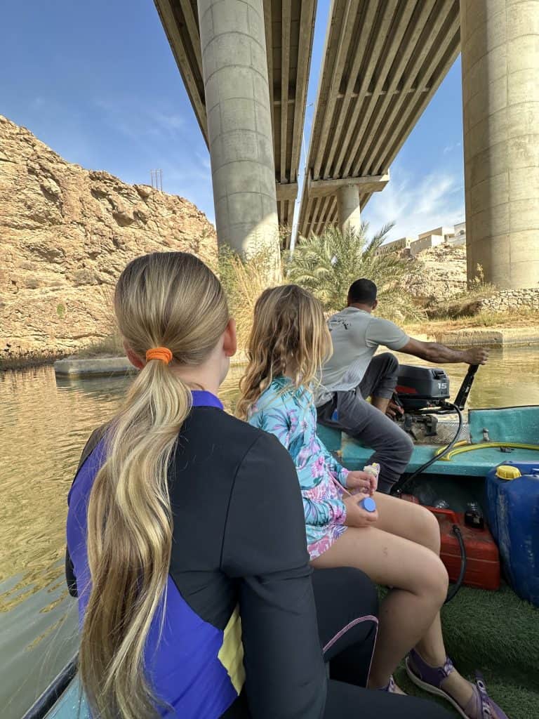 Two girls sat on motorboat looking ahead as they travel across the wadi to the walking trail