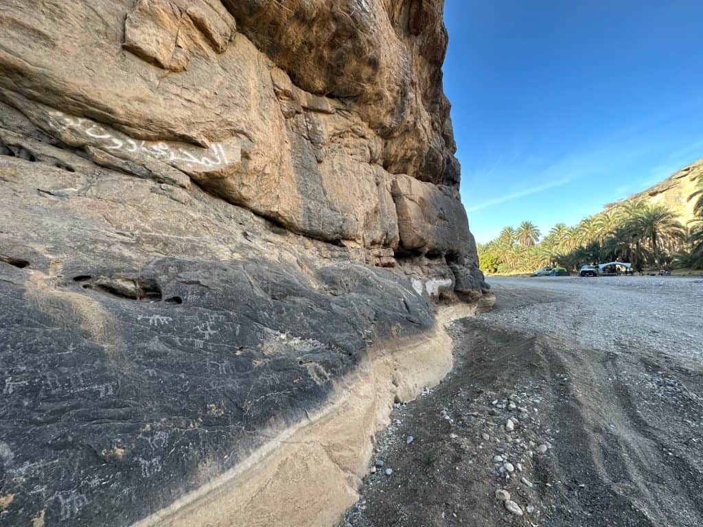 Petroglyths - an ancient rock art showing outlines of people, horses and camels - sketched onto the valley wall at Wadi Damm