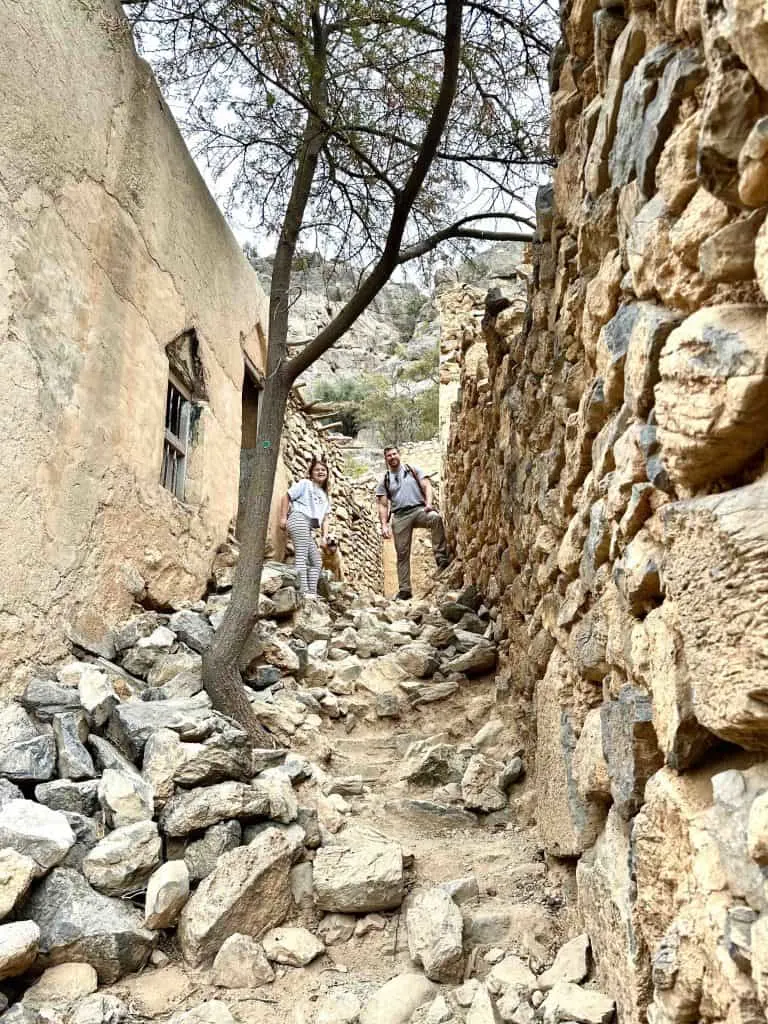 Mr Tin Box and daughter stand at the top of a rocky path through the abandoned village of Wadi Bani Habib
