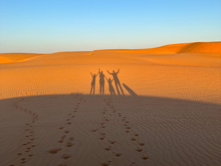 Shadows of family cast over the orange dunes of Wahiba Sands in Oman
