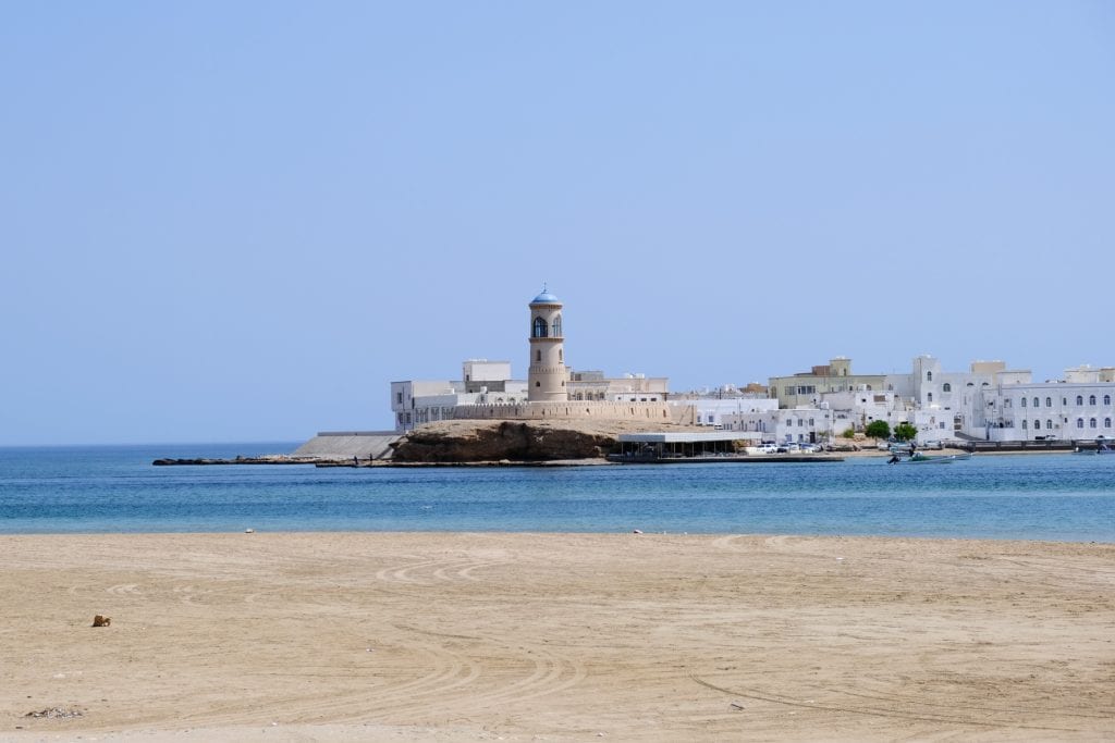 A view across Sur beach and harbour entrance towards Sur Lighthouse