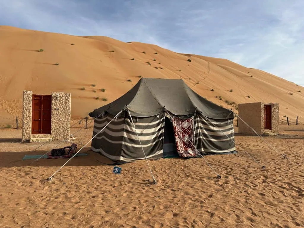 Traditional bedouin black and white striped tent in the orange sands of Wahiba Sands desert