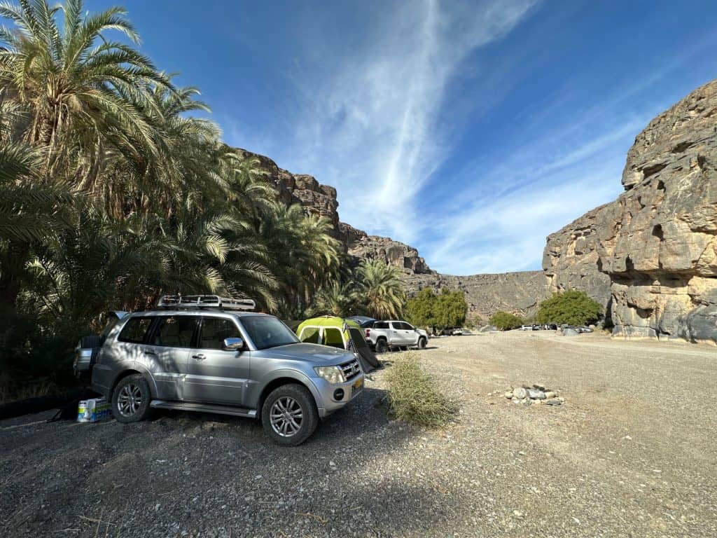Mitsubishi Pajero 4x4 vehicle parked in a large off road car park at the entrance to Wadi Damm. It has a tent beside it