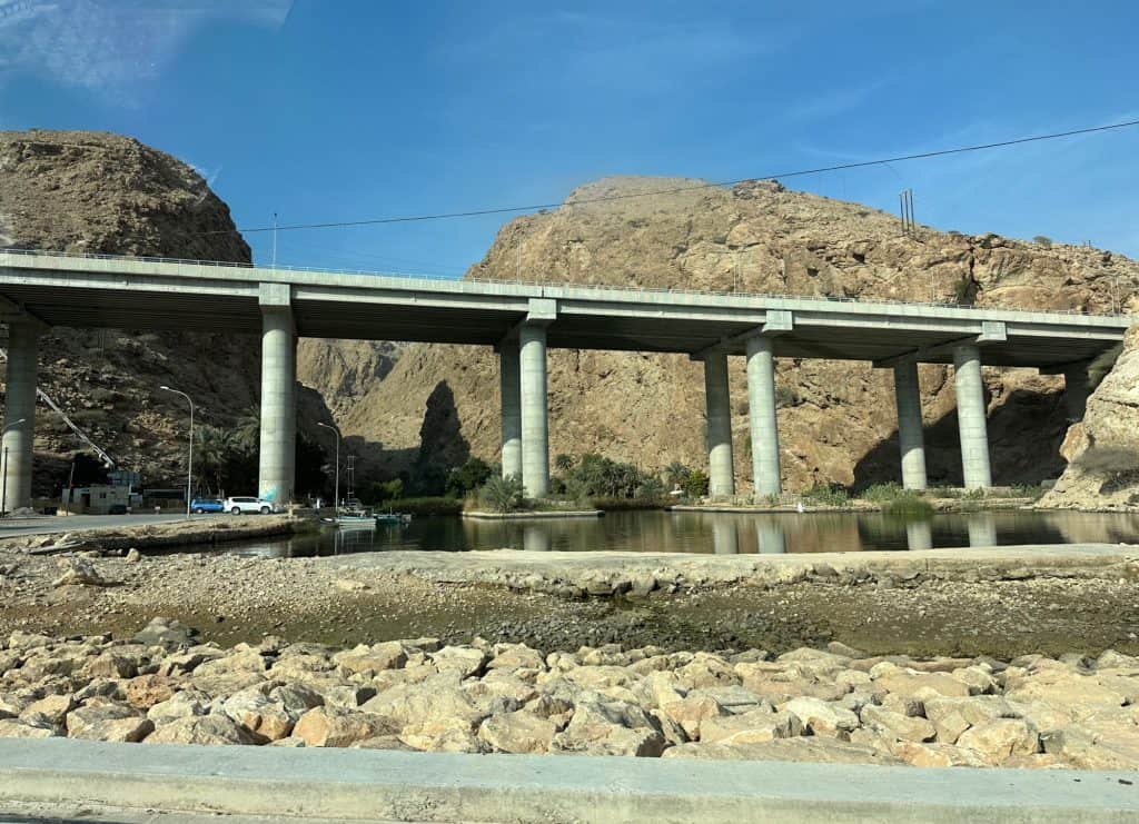A long shot of the viaduct over the wadi entrance should the wadi valley walls behind along with the car park and cafe at the back