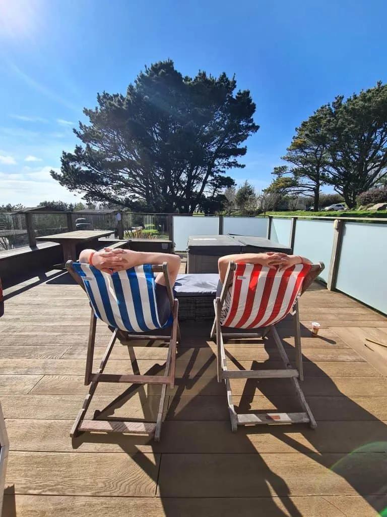 Family in stripy deck chairs sat on lodge deck enjoying some sun