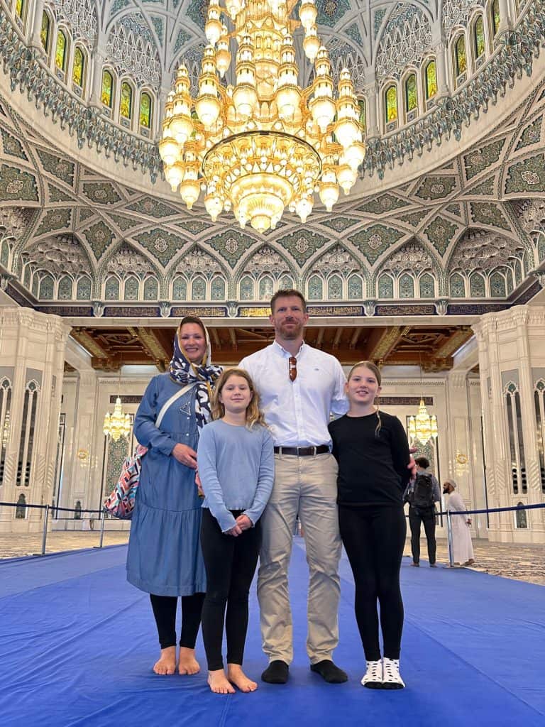 Our family stood on a blue carpet in the main prayer hall at the Grand Mosque with the two storey high chandelier behind us