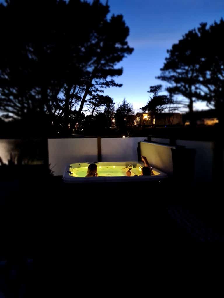 Family in the hot tub outside their lodge at night