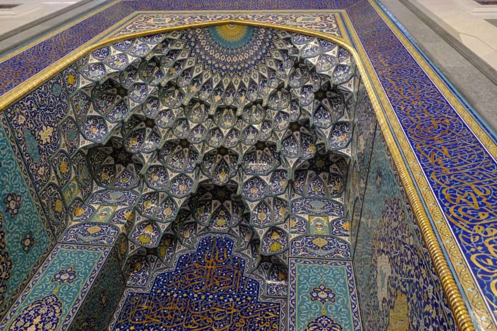 Looking up at the mihrab alcove at the front of the main prayer room. It is intricately decorated with blue, green and yellow mosaic