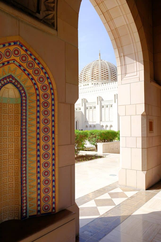 View of the mosque dome through an archway. In the foreground there is an alcove decorated with a colourful mosaic