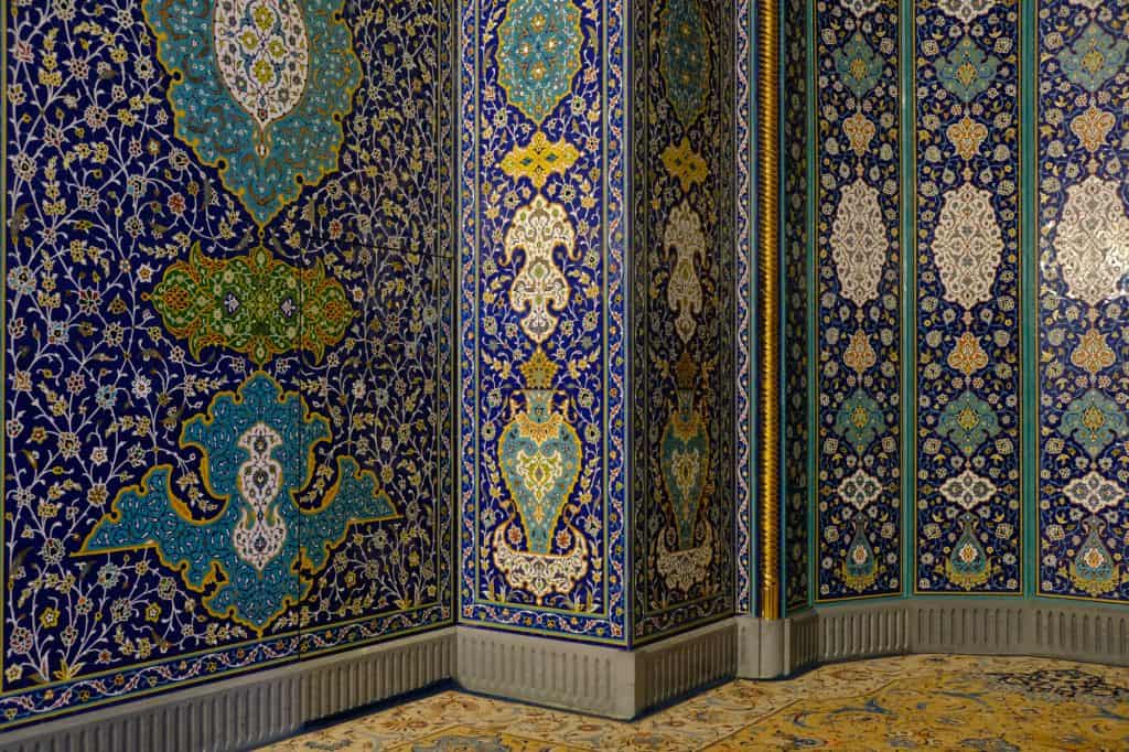 Intricate mosaic walks of the mihrab with he faint outline of a door on the left
