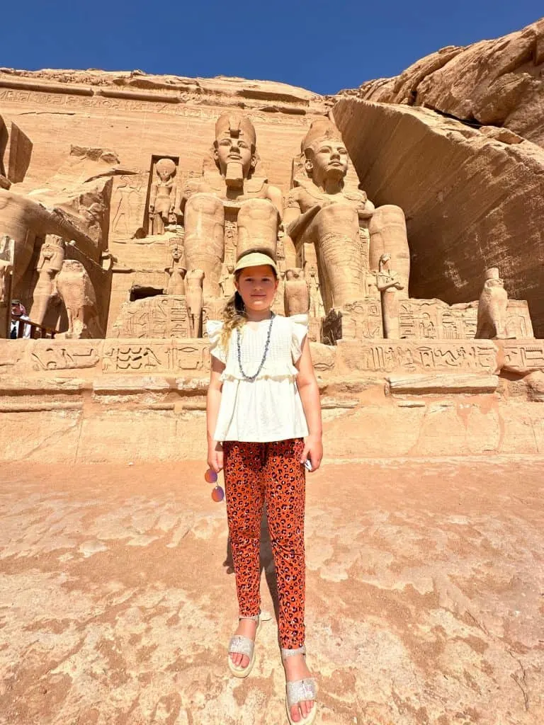 Child stood in front of the giant statues of the temple of Rameses II
