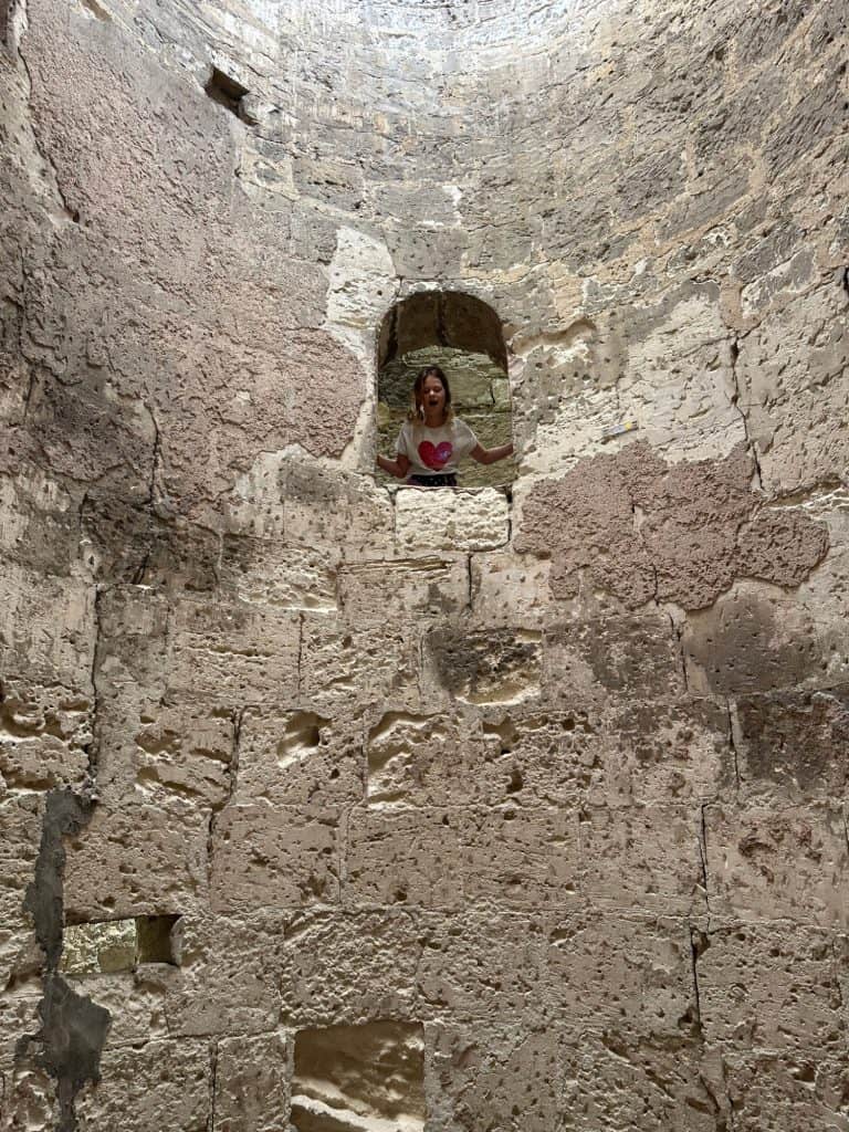 Girl looking through a small window in the entrance shaft of the catacombs