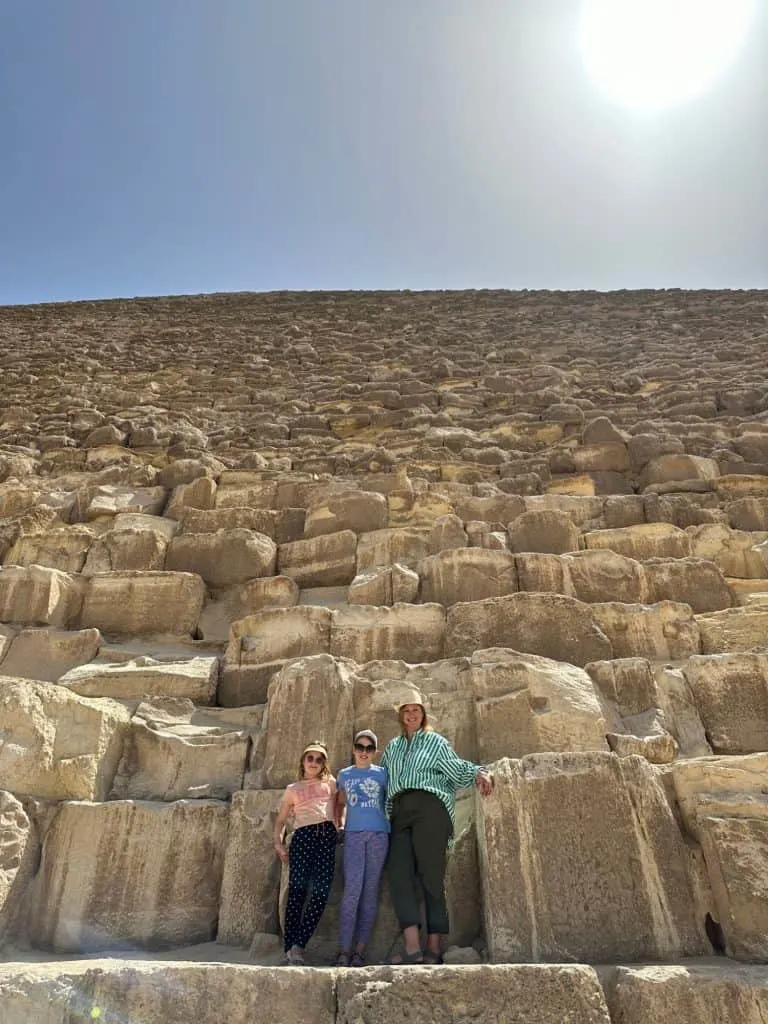 Claire and her daughters stand at the bottom of the Great Pyramid in Giza Stretching above them are thousands of sandstone blocks